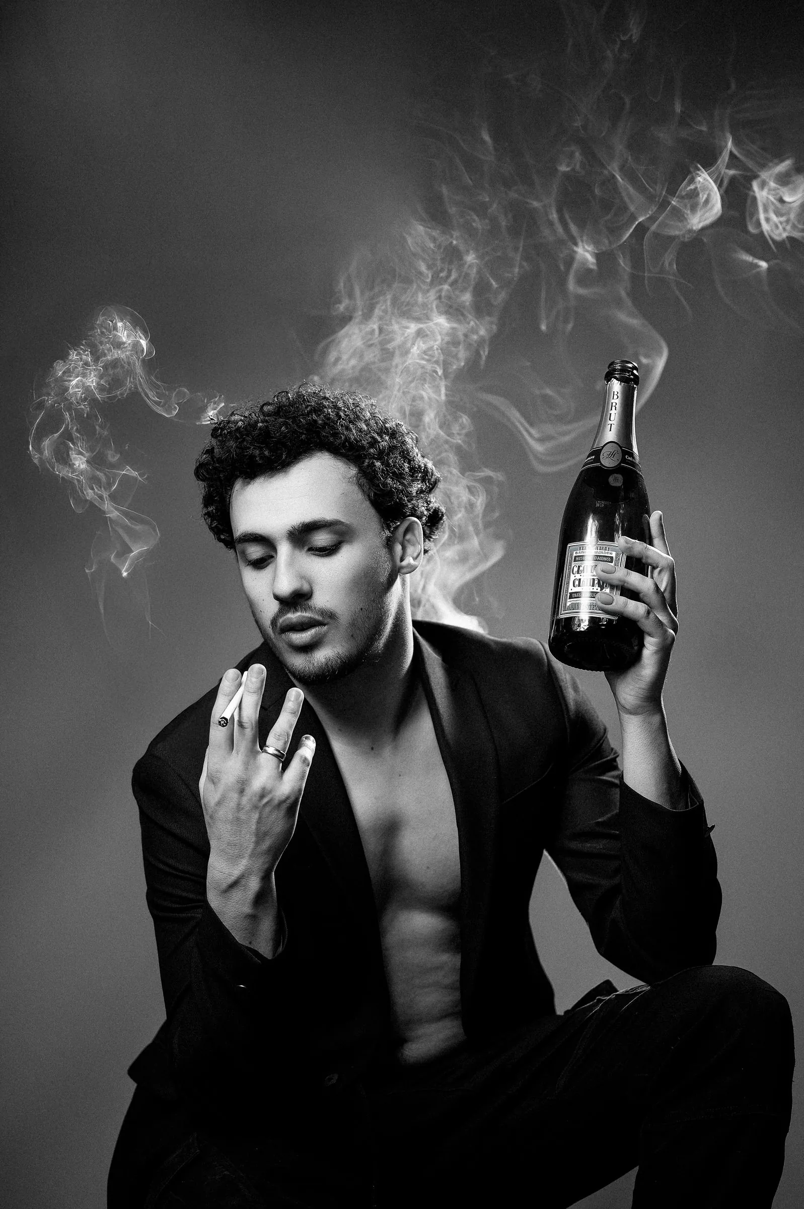 Portrait noir et blanc d’un comédien, fumée et bouteille de champagne