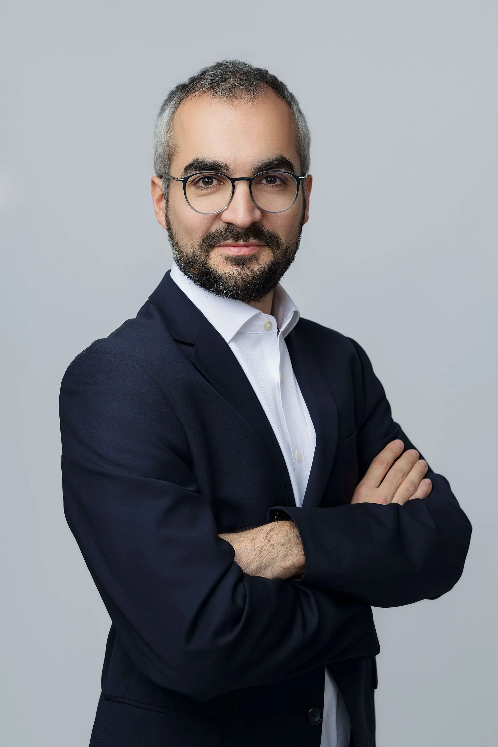 Portrait corporate d’un homme en costume, bras croisés, sur fond gris