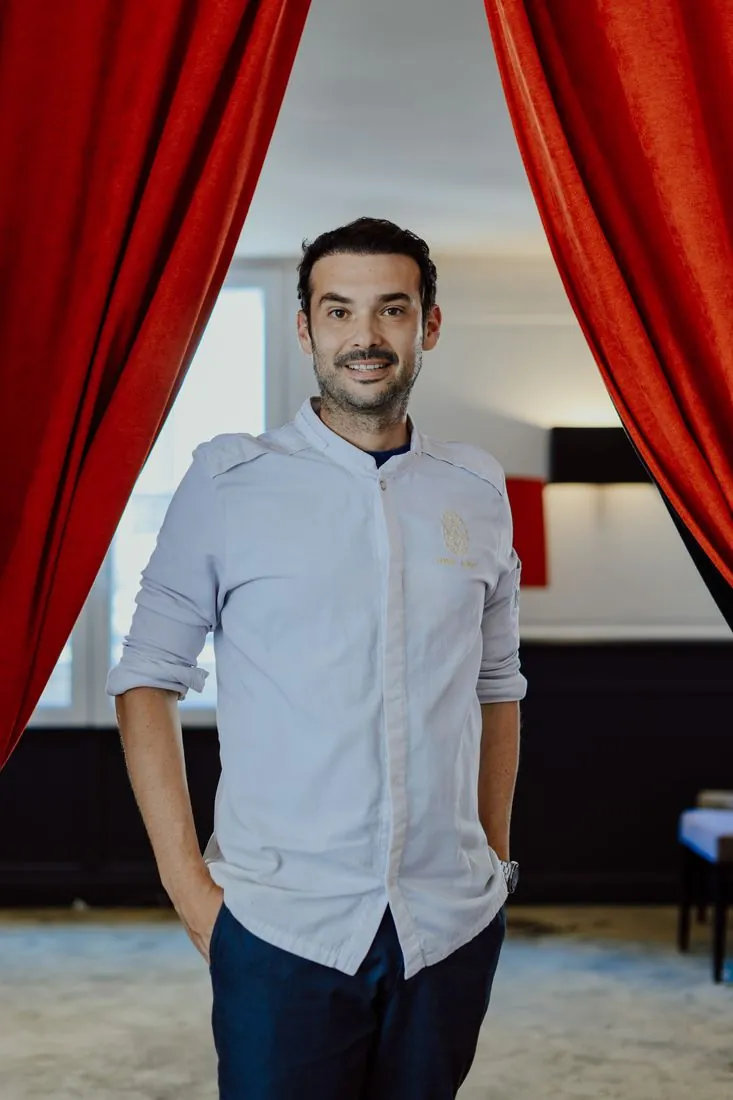 Portrait d’un chef devant des rideaux rouges