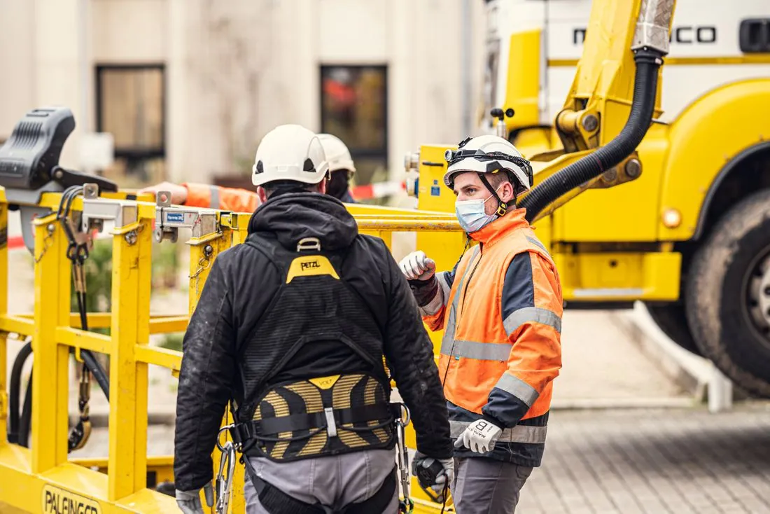 Techniciens en tenue de sécurité près d’une nacelle