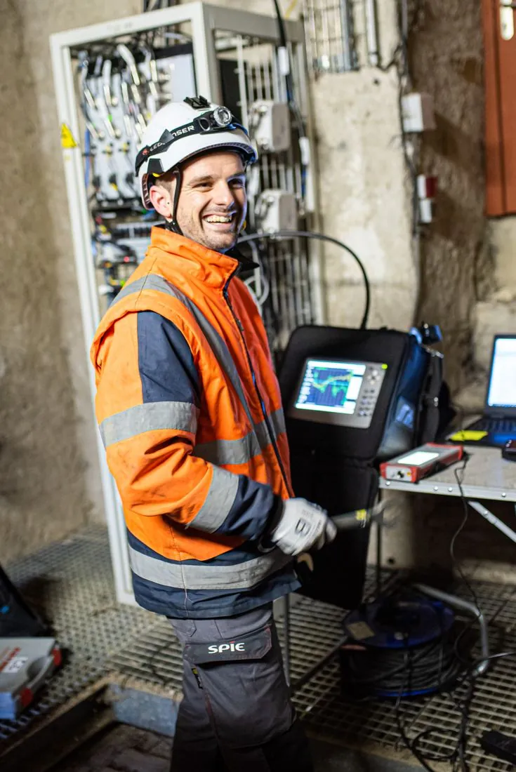 Technicien souriant devant une armoire électrique