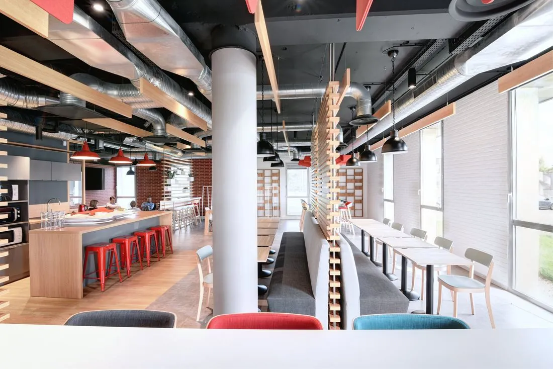 Espace de restauration d’entreprise avec îlot central et tabourets rouges