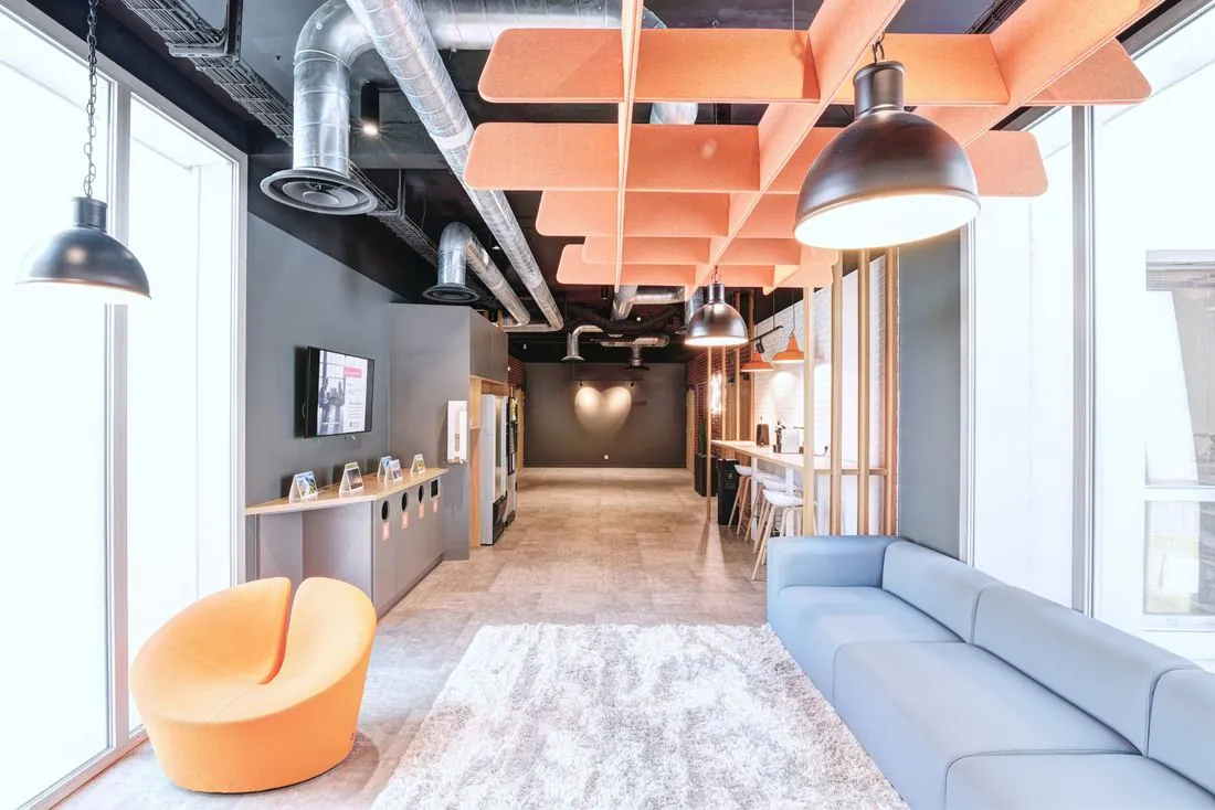 Espace détente avec canapé bleu et plafond acoustique orange