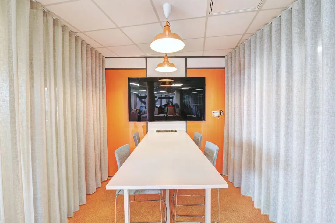 Salle de réunion avec mur orange et écran