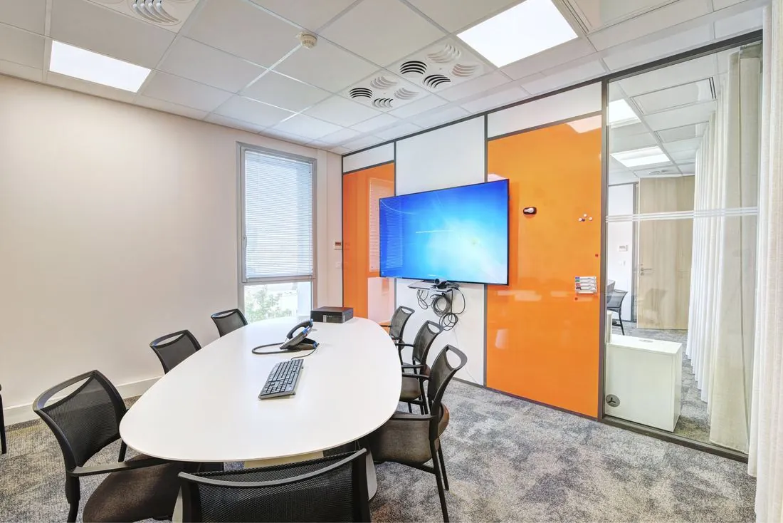 Salle de réunion avec table ovale et écran interactif