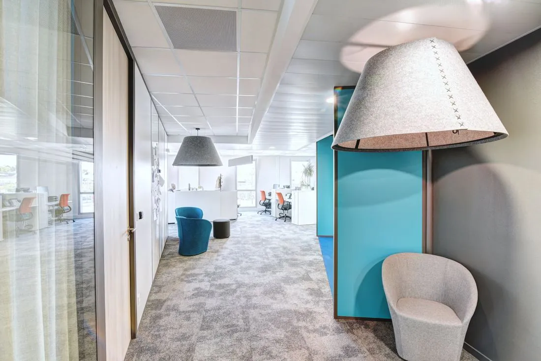 Open space avec cabine acoustique bleue et fauteuil