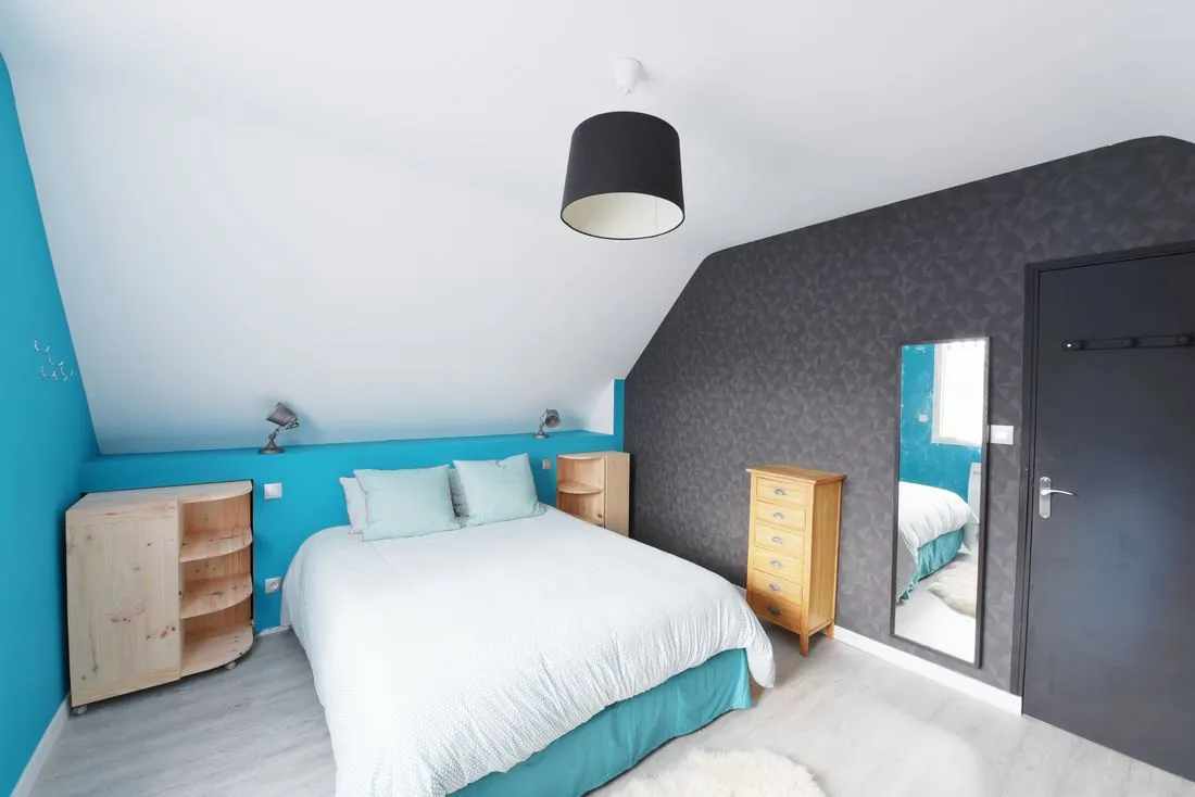 Chambre avec mur bleu canard et linge de lit blanc