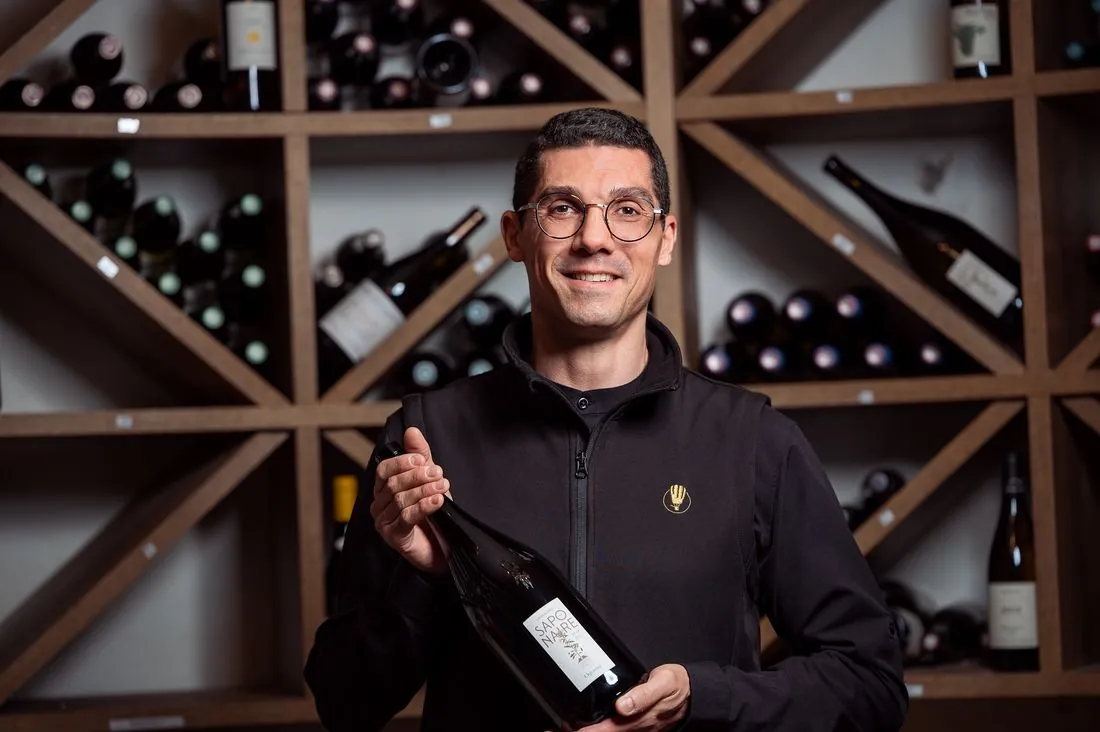 Sommelier présentant une bouteille devant la cave à vin