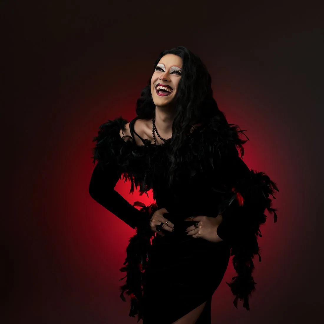 Portrait artistique drag, plumes noires sur fond rouge