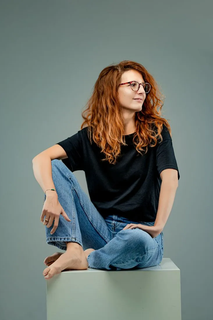 Portrait d’une femme rousse assise sur un cube