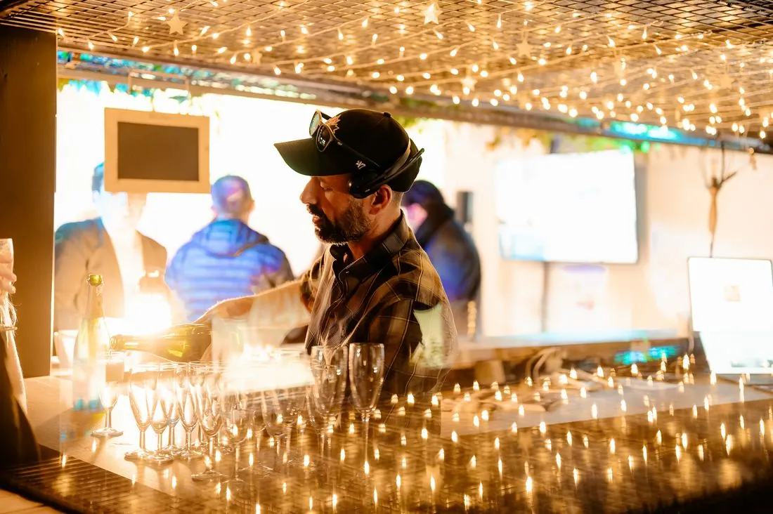 Barman servant sous des guirlandes lumineuses lors d’un événement