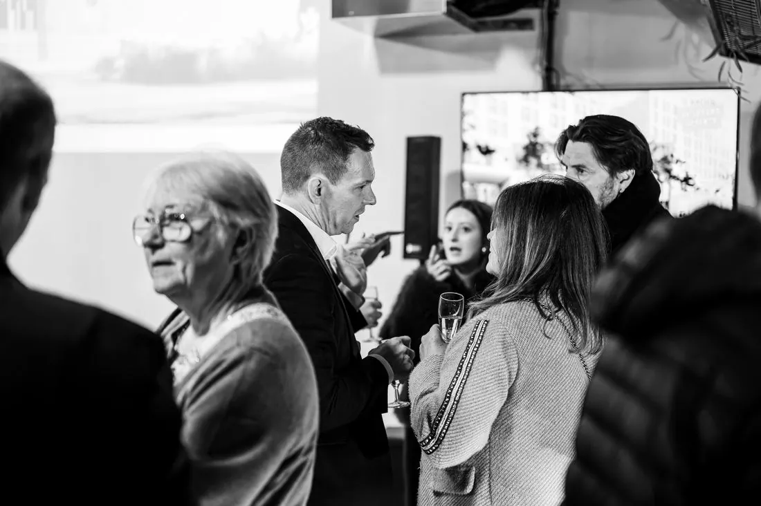 Échanges entre invités lors d’un événement, en noir et blanc