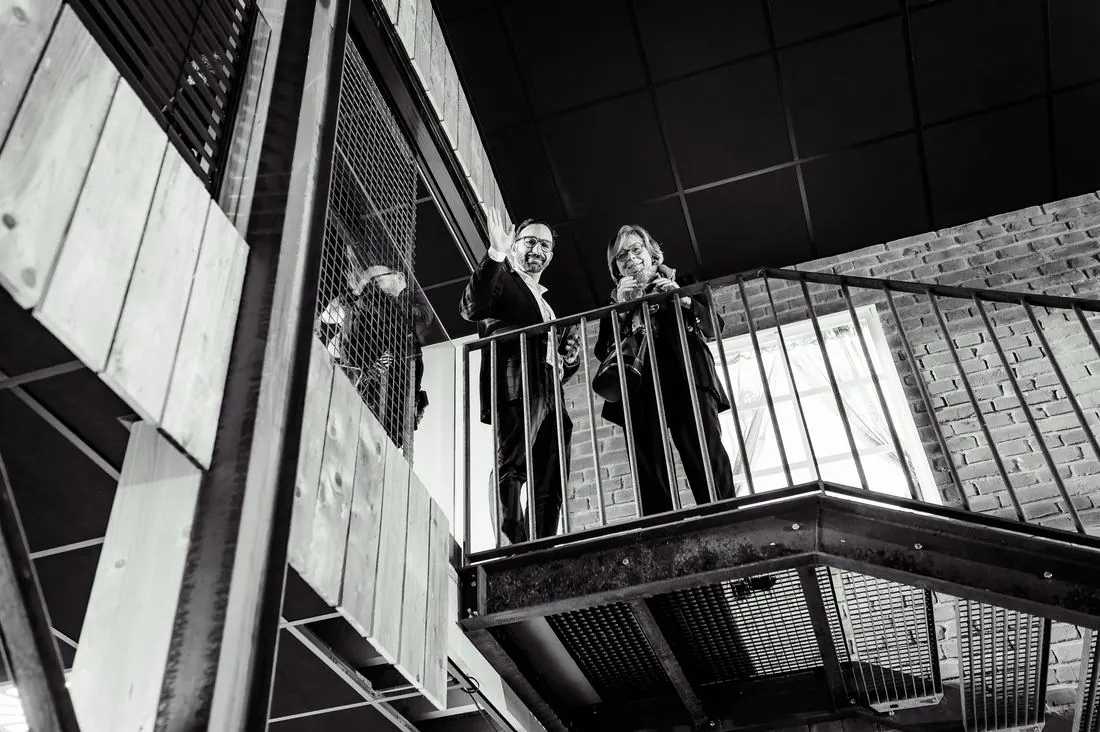 Invités accoudés à une passerelle métallique, en noir et blanc
