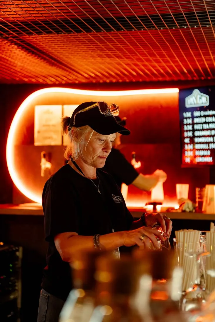 Barmaid préparant un cocktail sous une lumière rouge
