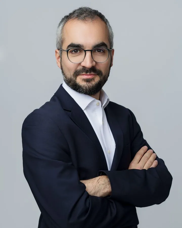 Portrait corporate d’un homme en costume, bras croisés, sur fond gris